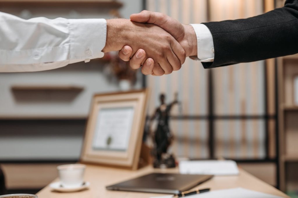 close-up-photo-of-people-shaking-hands-8112172 Close-up of a handshake between two professionals in a modern office setting, emphasizing partnership and agreement.